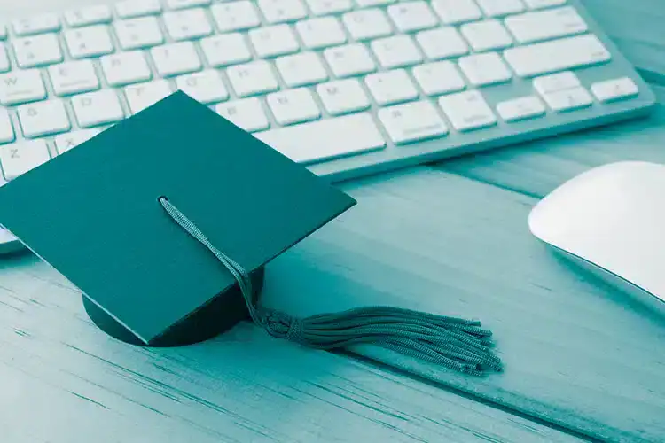 un birrete de graduación colocado junto a un teclado