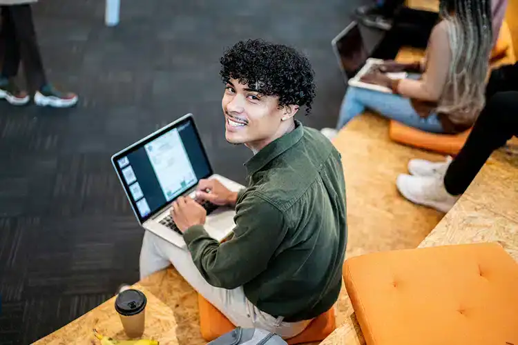 Un étudiant masculin travaillant sur un devoir universitaire sur son ordinateur portable