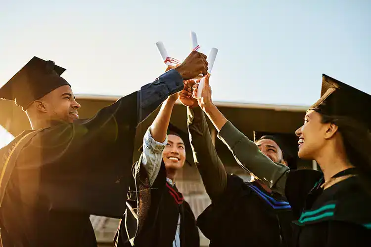 Hochschulabsolventen, die ihren Abschluss in den Händen halten und den Tag ihres Studienabschlusses feiern