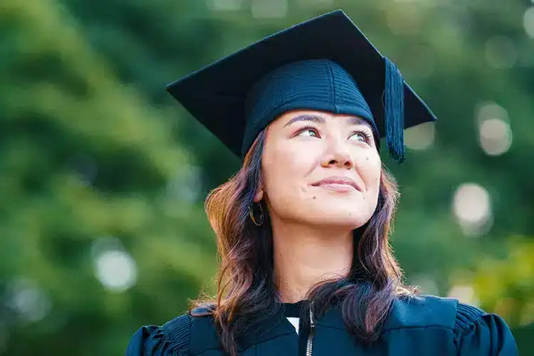 eine stolze College-Absolventin posiert für ein Foto am Tag der Abschlussfeier