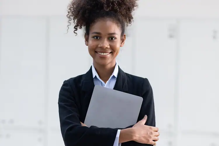 a female college student holding a notebook and posing for the camera